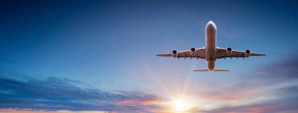 Commercial aircraft in the sky with setting sun in the background