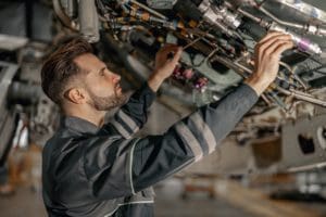 Male aviation maintenance technician repairing airplane in hangar